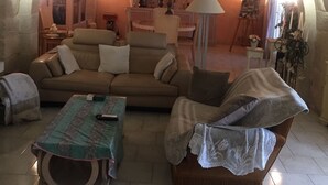 A cozy living room with a stone arch, a sofa, a coffee table, and a small table with a lamp. - Mas provençal en pierre  (UZES)