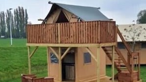 A wooden cabin with a balcony, a staircase, and a door.