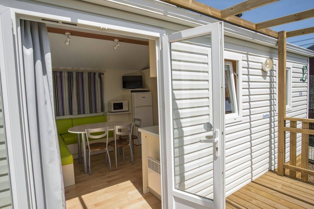 A compact mobile home with a kitchenette, a dining area, and a small seating space.