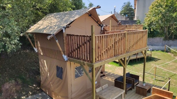 A wooden playhouse with a balcony and a deck area.