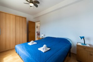 A bedroom with a large bed, wooden wardrobe, and a ceiling fan.