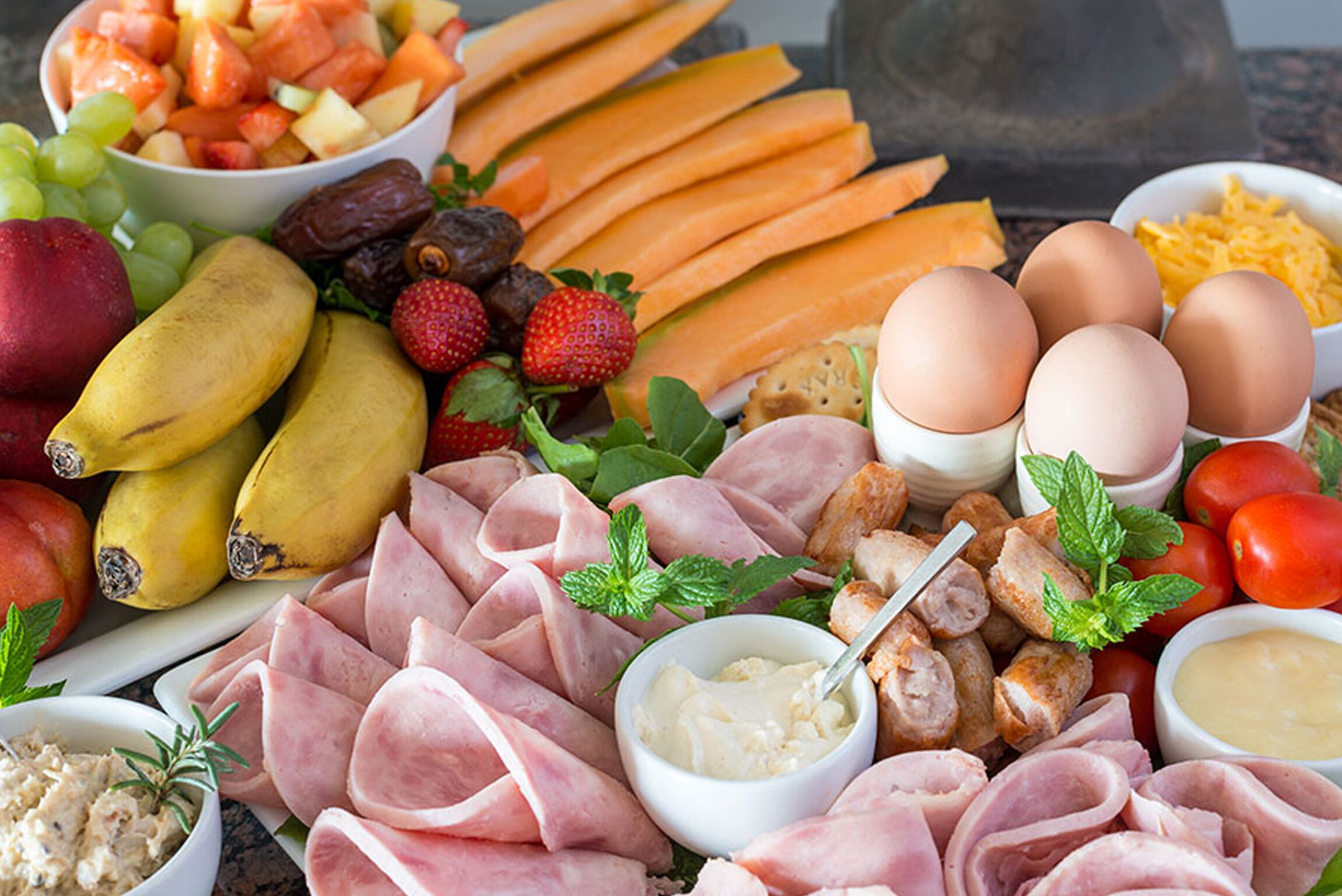 A variety of food items including fruits, vegetables, meats, and eggs arranged on a table.