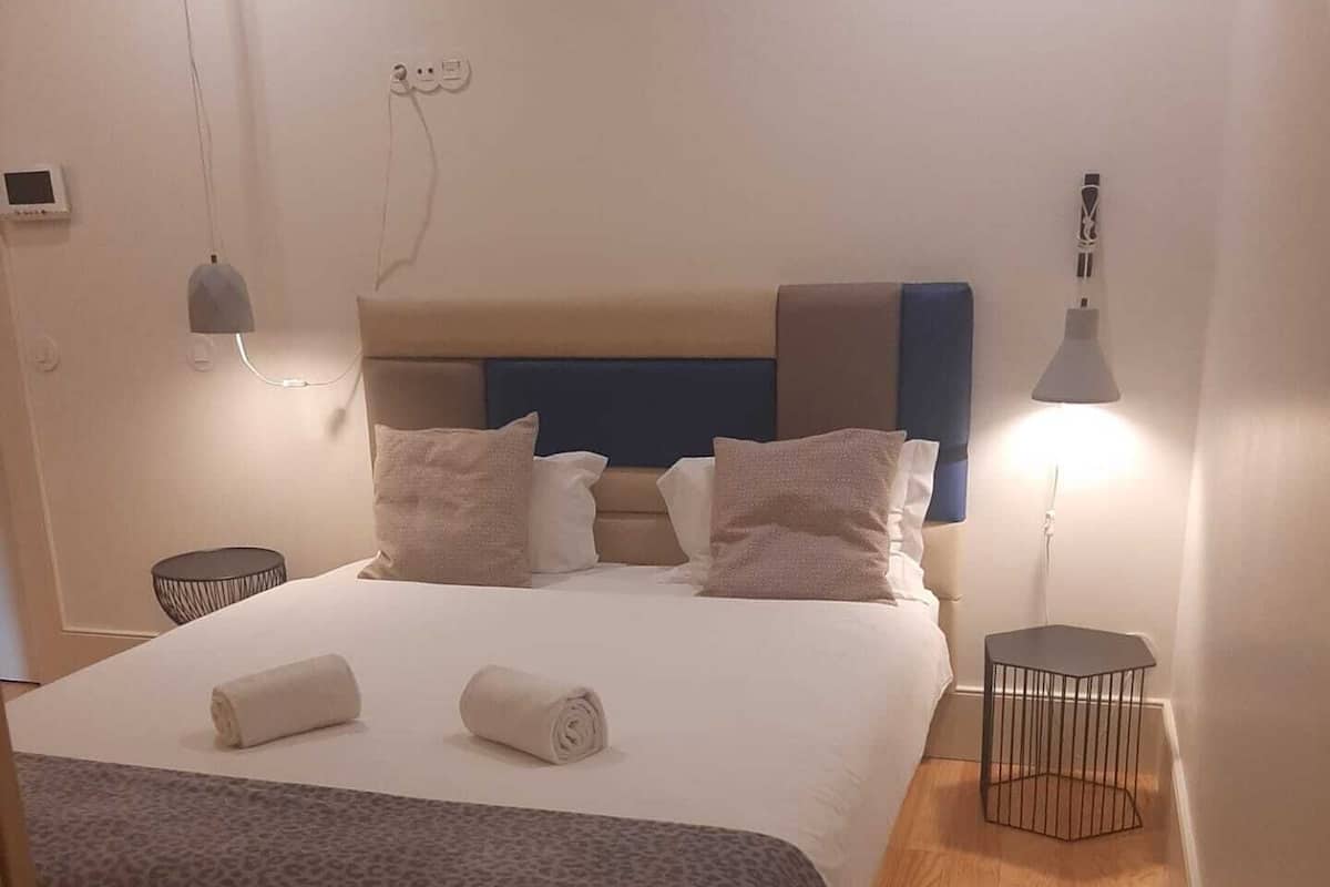 A bedroom with a bed, bedside lamps, a round table, and a chair.