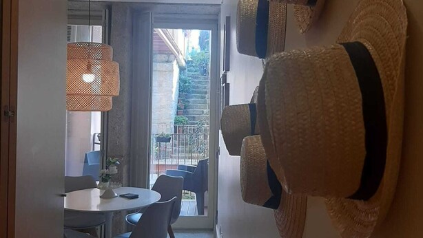 A modern dining area with a round table and chairs, a hanging light fixture, and a view of the outside. - ORM - Almada Apartments (Porto)
