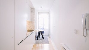 A modern hallway with a kitchen area, a dining table, and a phone on the wall. - ORM - Almada Apartments (Porto)
