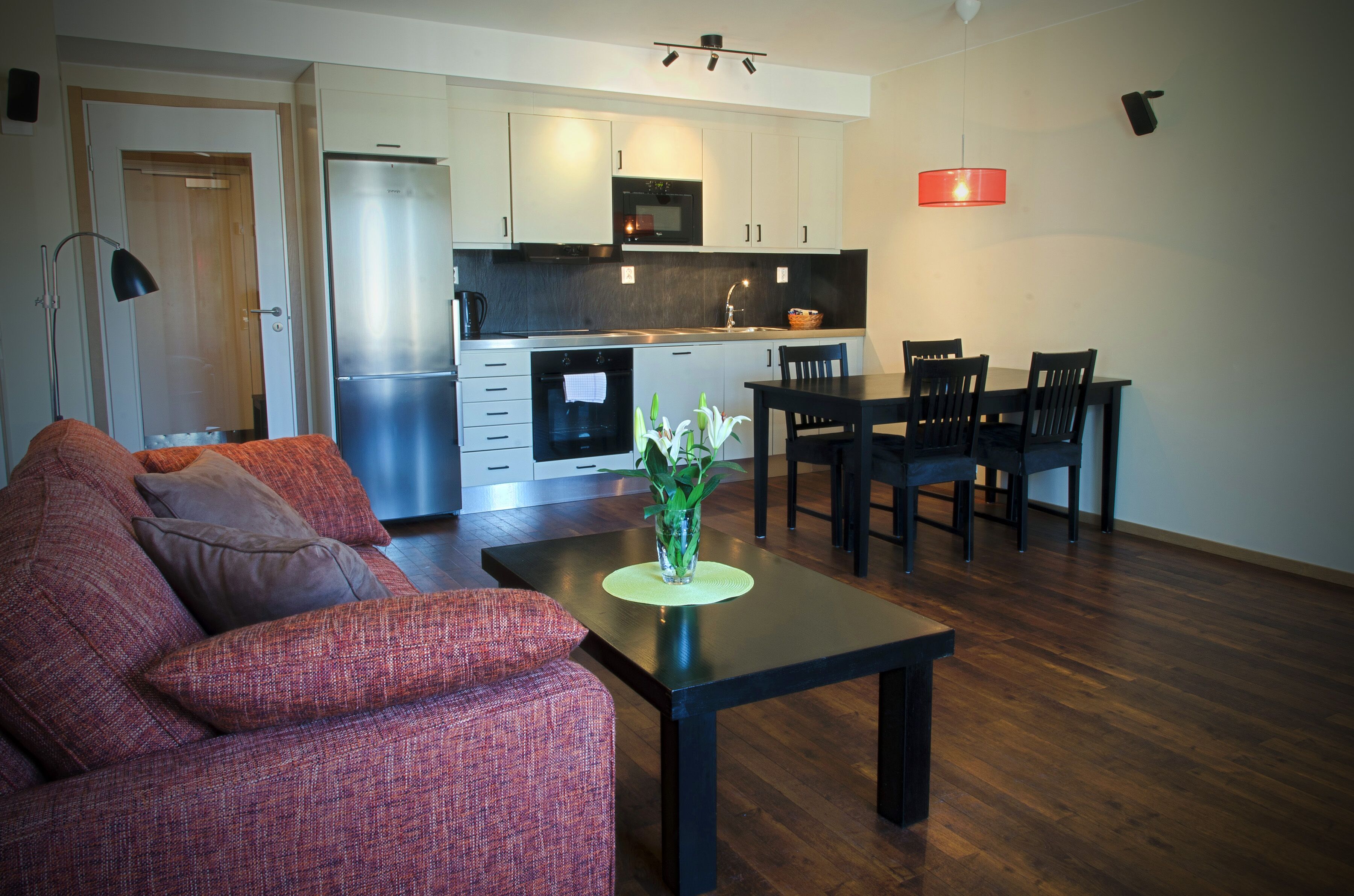 A modern kitchen with stainless steel appliances, a dining area with a table and chairs, and a living room with a sofa.
