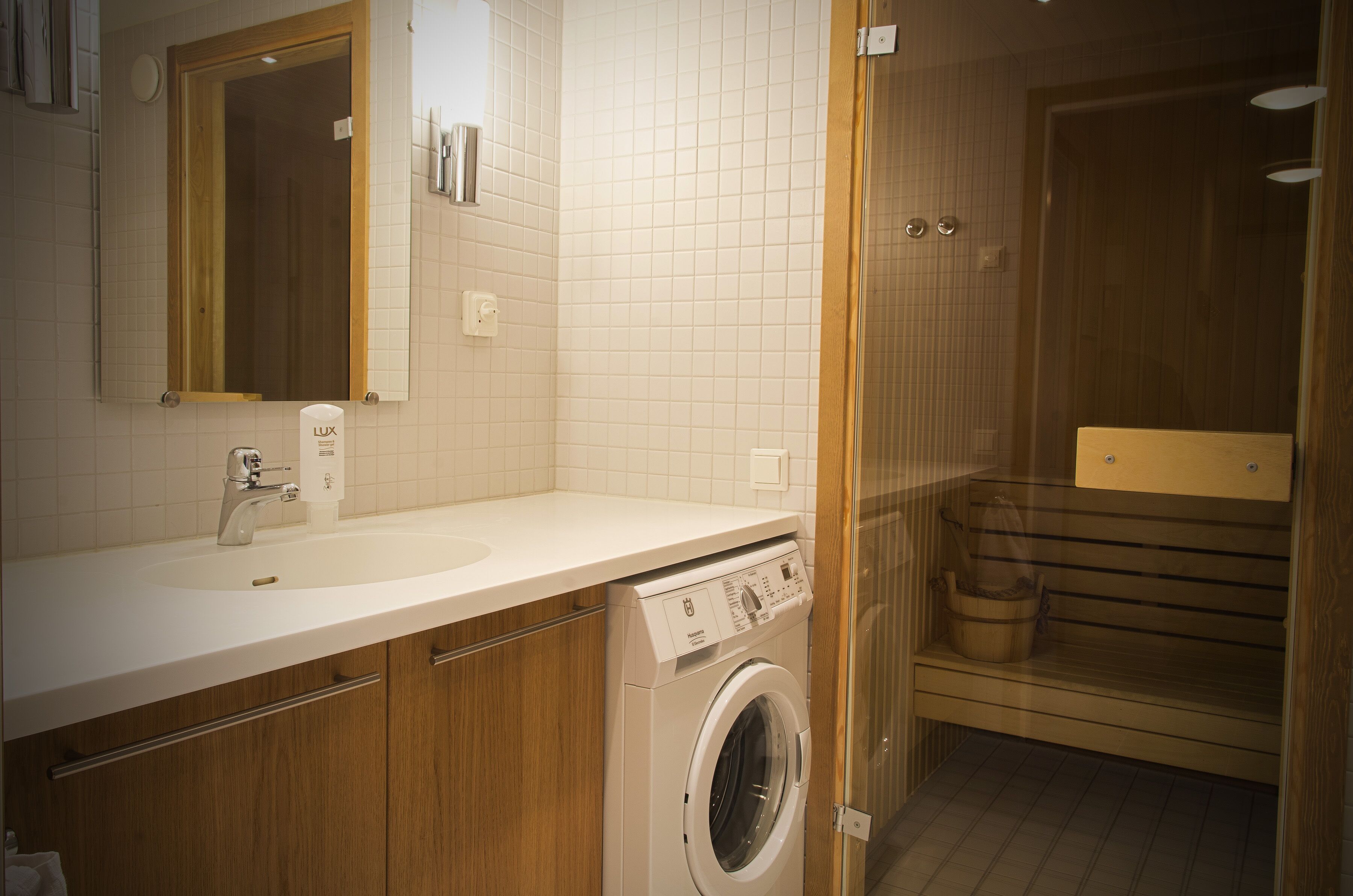 A modern bathroom with a built-in washing machine, a sink, and a mirror.