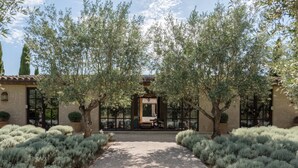 A courtyard with a central archway, surrounded by olive trees and a gravel path. - Spectacular unique villa in the Emporda (Calabuig)