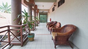A covered corridor with wicker chairs, potted plants, and a tiled floor. - D'Jawi Bella Hotel (Sungai Jawi)