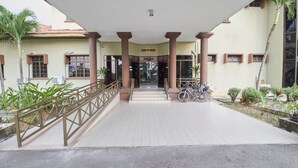 A building entrance with a covered walkway, columns, and a sign above the door. - D'Jawi Bella Hotel (Sungai Jawi)