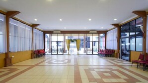 A spacious indoor area with a tiled floor, red chairs arranged in rows, and large windows with curtains. - D'Jawi Bella Hotel (Sungai Jawi)