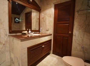 A bathroom with a marble sink, wooden vanity, and a toilet.