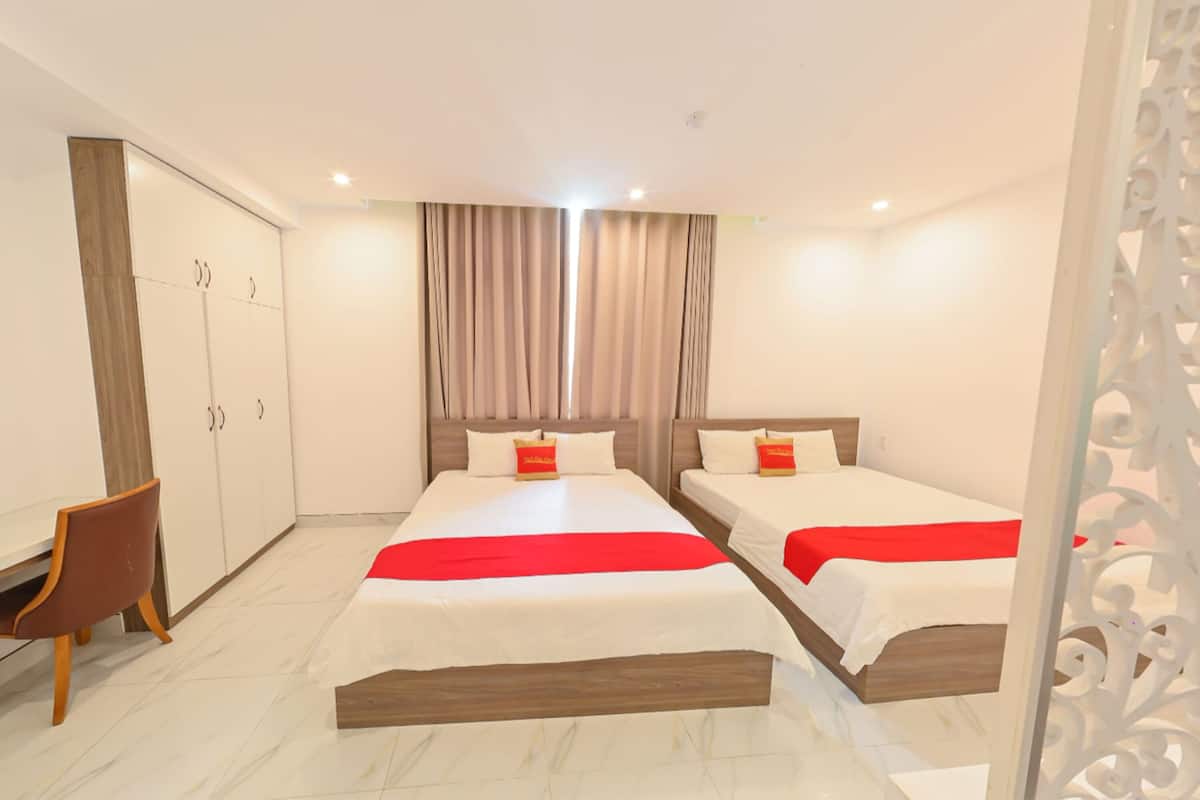 A hotel room with two beds, a desk, and a wardrobe.