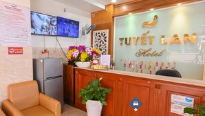 Ein Hotelrezeptionstresen mit Fernseher, einem Schild mit der Aufschrift 'TUYET LAN Hotel' und einer Pflanze.
