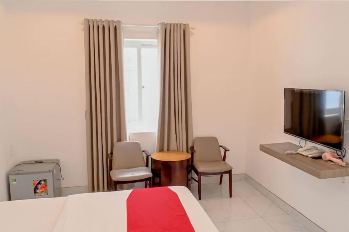 Une chambre d’hôtel comprenant un lit, deux chaises, une petite table, un téléviseur et un mini-bar.