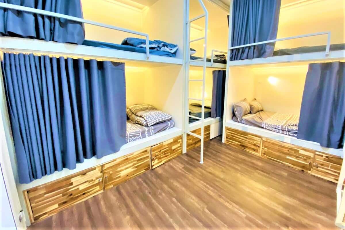 Ein Schlafsaalzimmer mit Etagenbetten, Holzboden und Vorhängen.