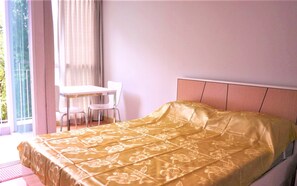 A bedroom with a bed, a desk, and chairs.