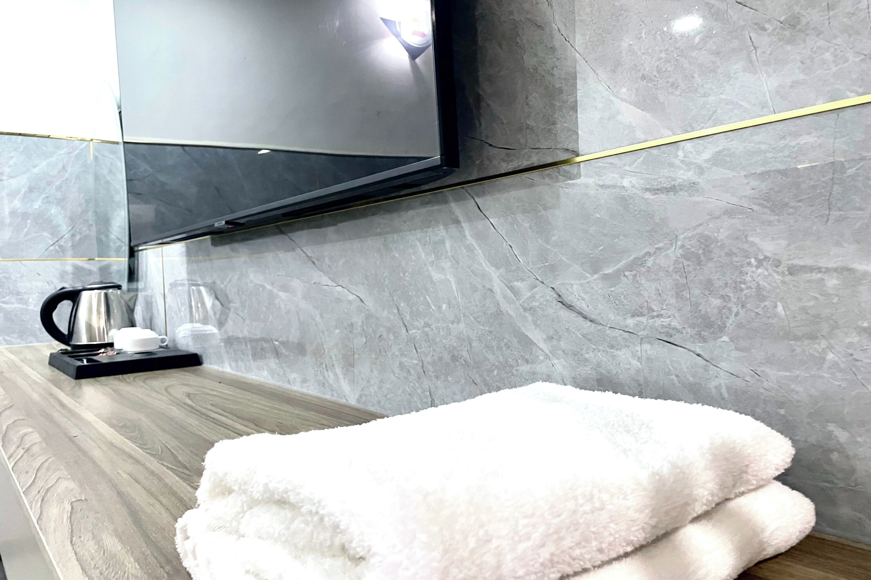 Un bagno con un mobile lavabo in legno, un asciugamano bianco e soffice, una macchina da caffè nera e uno specchio.
