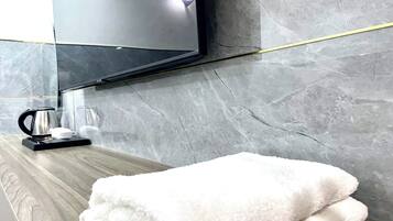 Un bagno con un mobile lavabo in legno, un asciugamano bianco e soffice, una macchina da caffè nera e uno specchio.