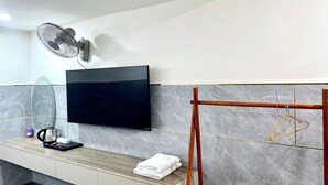 Un bany modern amb televisió penjada, porta tovalloles, un mirall i una cafetera a la tauleta.