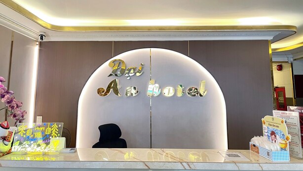 Una recepció amb un rètol que diu 'Dai An Hotel', una càmera de seguretat i un mostrador amb diversos objectes.