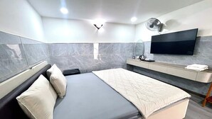 Habitació d'hotel moderna amb un llit, una televisió penjada a la paret i un petit escriptori amb un mirall.