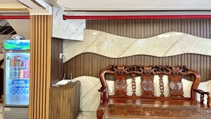Habitació amb un sofà de fusta, una paret de marbre i una màquina expenedora.