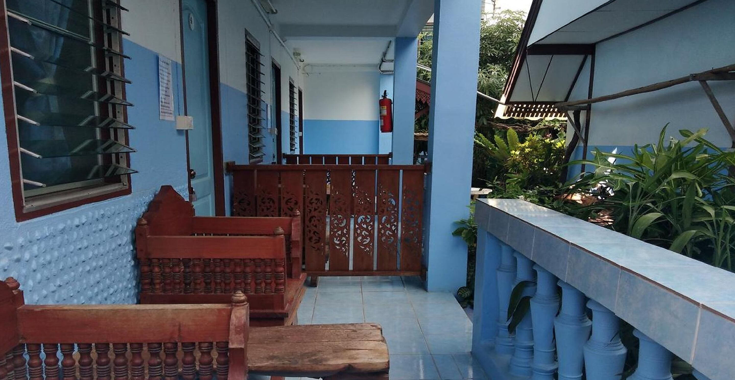 A covered outdoor area with a wooden bench, a metal gate, and a tiled floor.