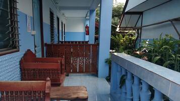 A covered outdoor area with a wooden bench, a metal gate, and a tiled floor.