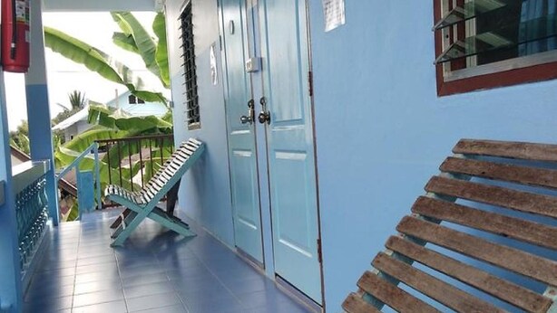 Un espacio al aire libre techado con un banco de madera, puertas azules y suelo de baldosas.