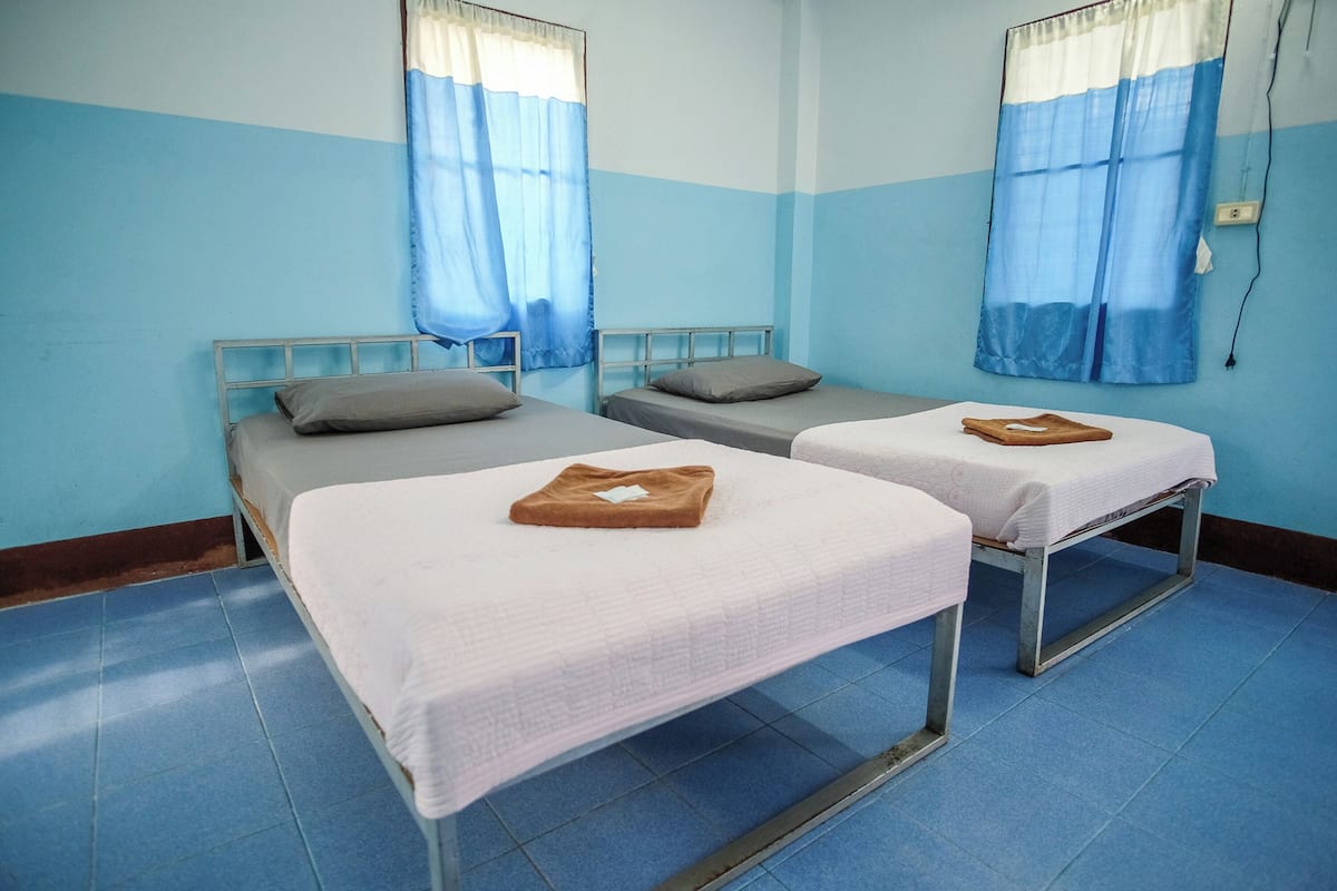 Une chambre avec deux lits simples, chacun étant équipé d’un oreiller et d’une serviette pliée.
