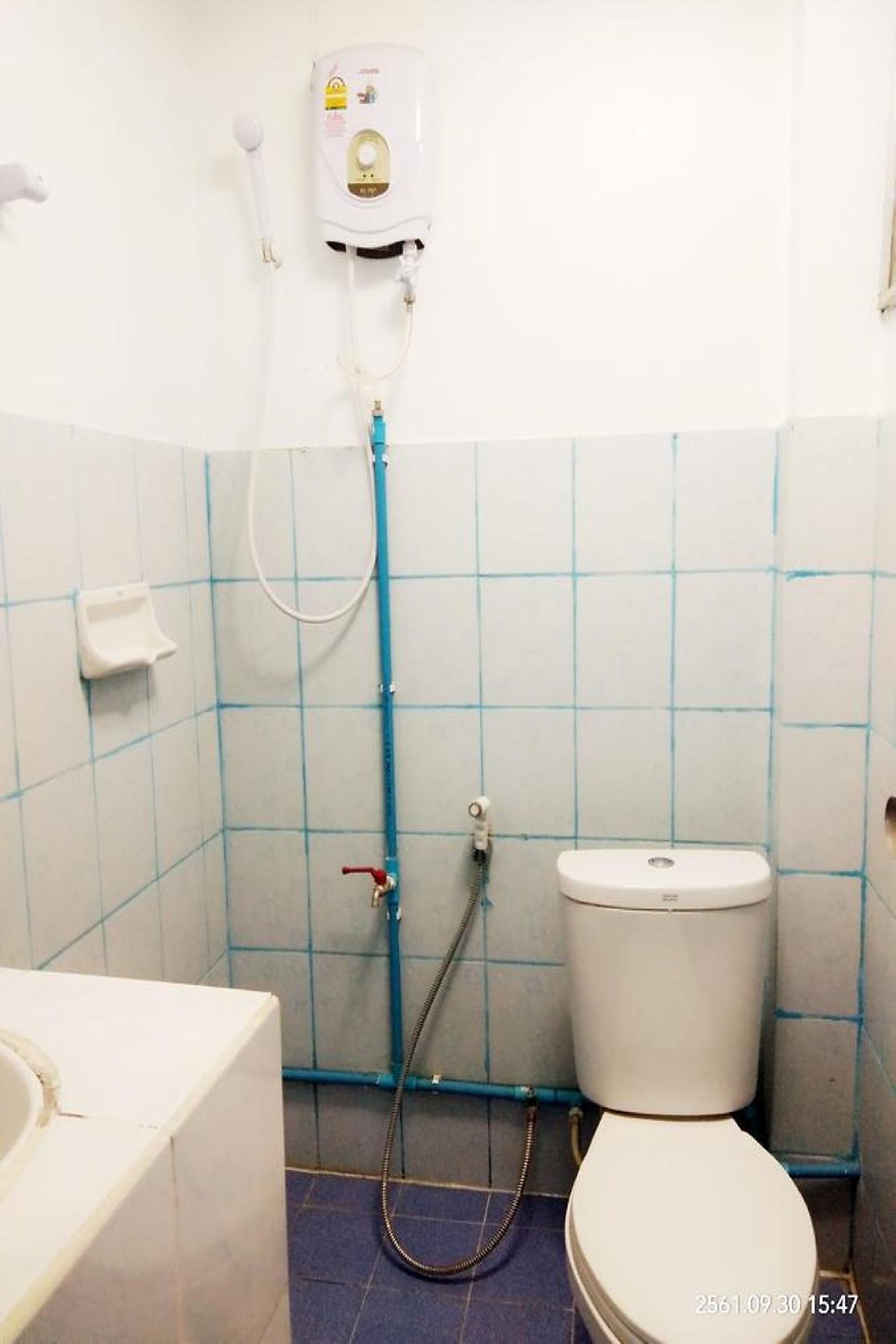 A bathroom with a toilet, a hand dryer, and a wall-mounted water heater.