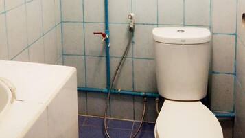 A bathroom with a toilet, a hand dryer, and a wall-mounted water heater.