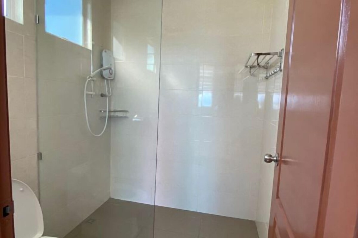 Uma casa de banho com sanita, chuveiro e porta.