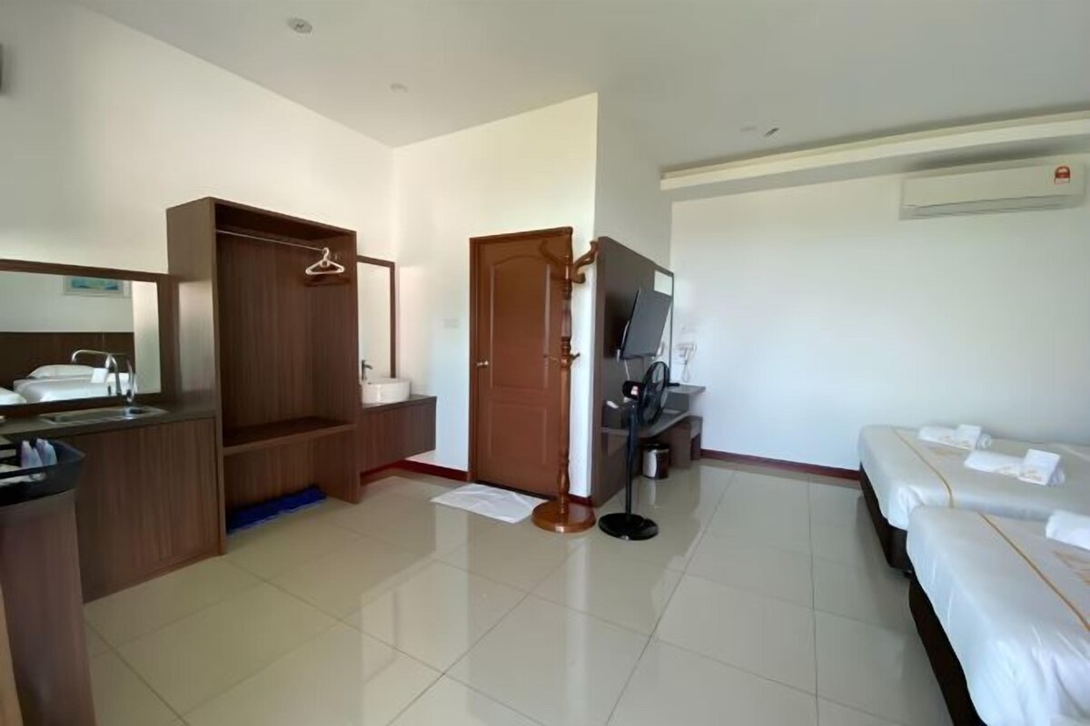 Quarto de hotel com cama, televisão, escrivaninha, cadeira, armário e banheiro.