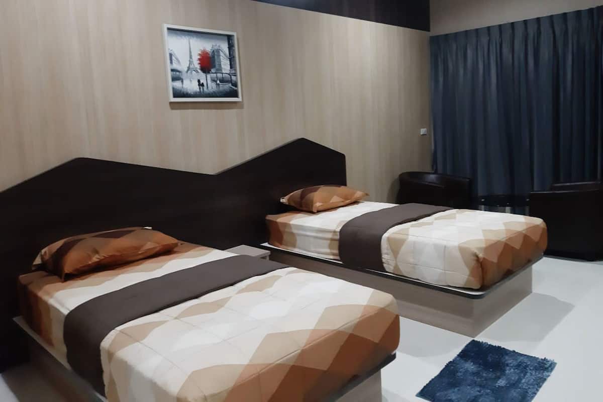 Una habitación de hotel con dos camas, un cabecero oscuro, un cuadro en la pared y una cortina azul.