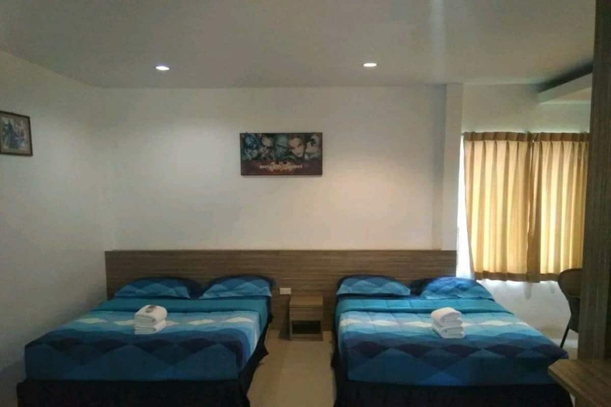 Una habitación de hotel con dos camas individuales, un cuadro en la pared y una ventana con cortinas.