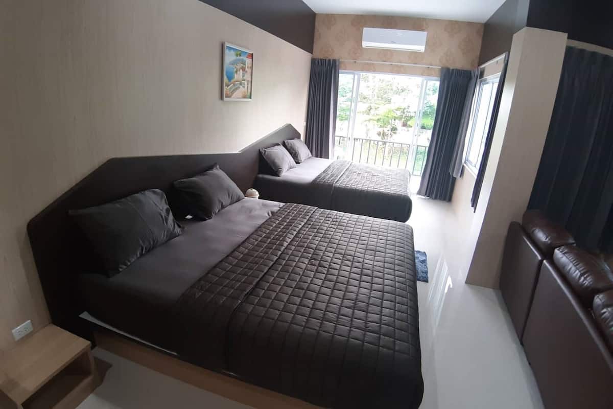 Un dormitorio moderno con una cama grande, otra más pequeña, un escritorio y un balcón con cortinas.