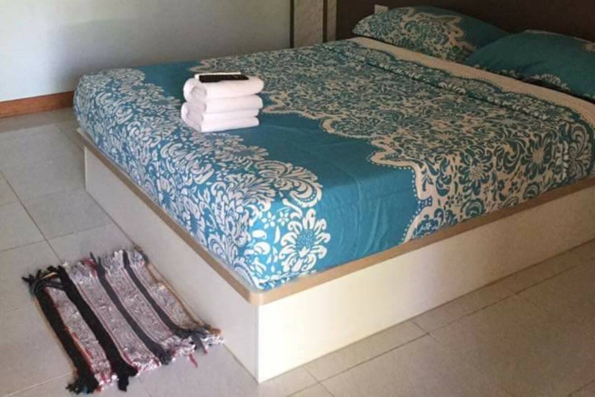 Un dormitorio con una cama, aire acondicionado en la pared y dos cuadros enmarcados.