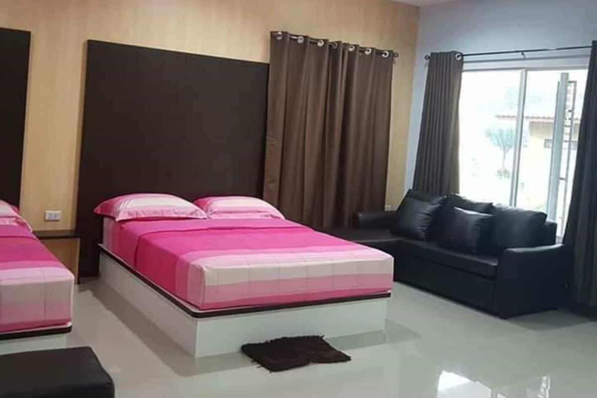 Una habitación de hotel moderna con una cama grande, un sofá y un ventanal con cortinas.