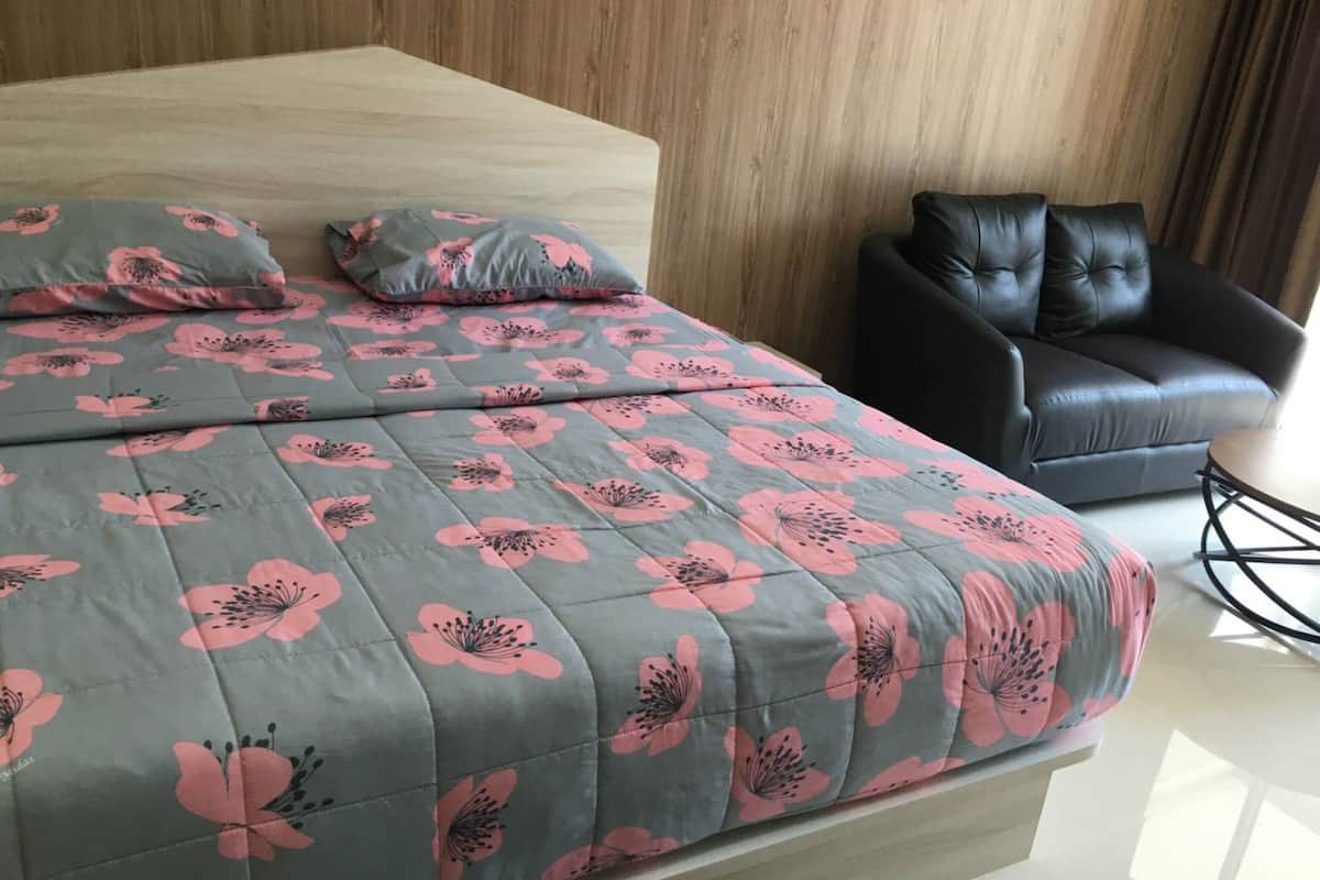 Un dormitorio moderno con una cama, un sofá de cuero oscuro y una pequeña mesa redonda.