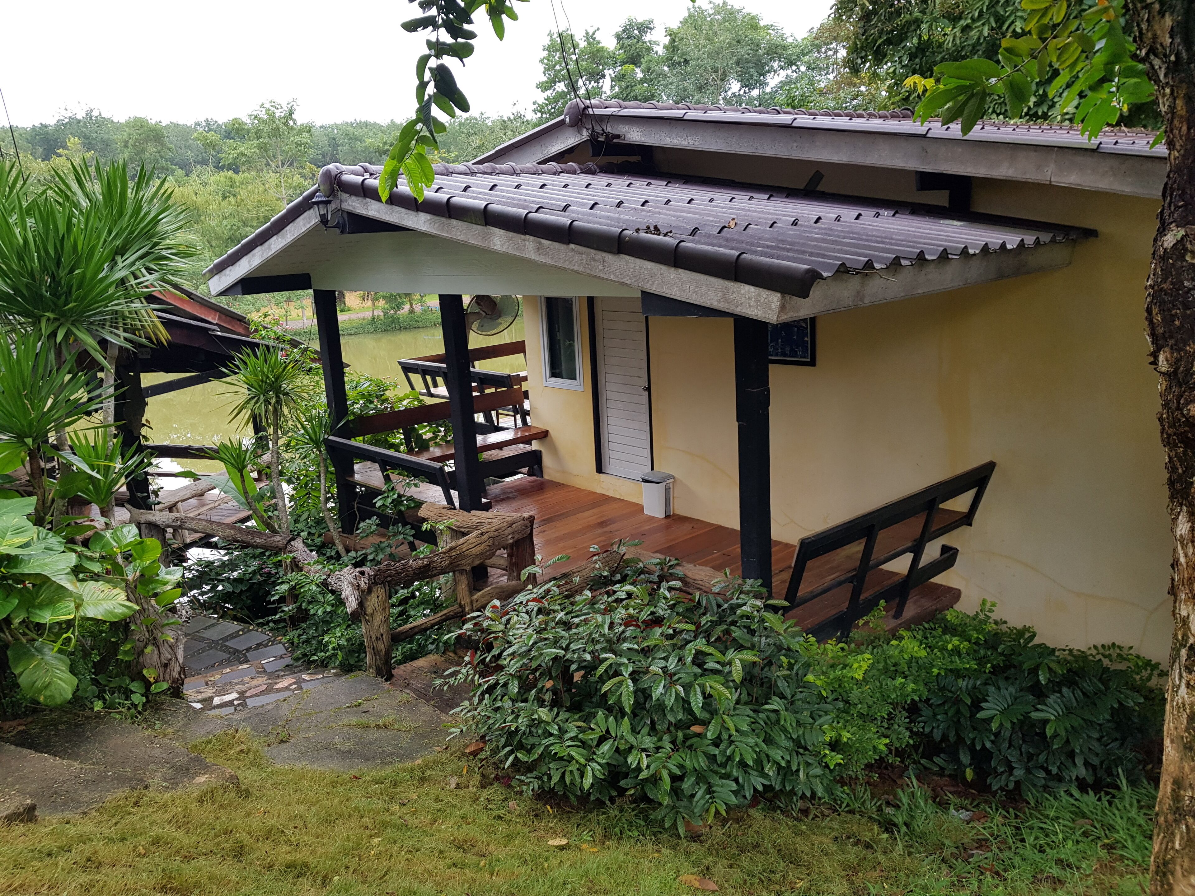 A traditional-style building with a tiled roof, wooden benches, and a stone pathway leading to a covered seating area.