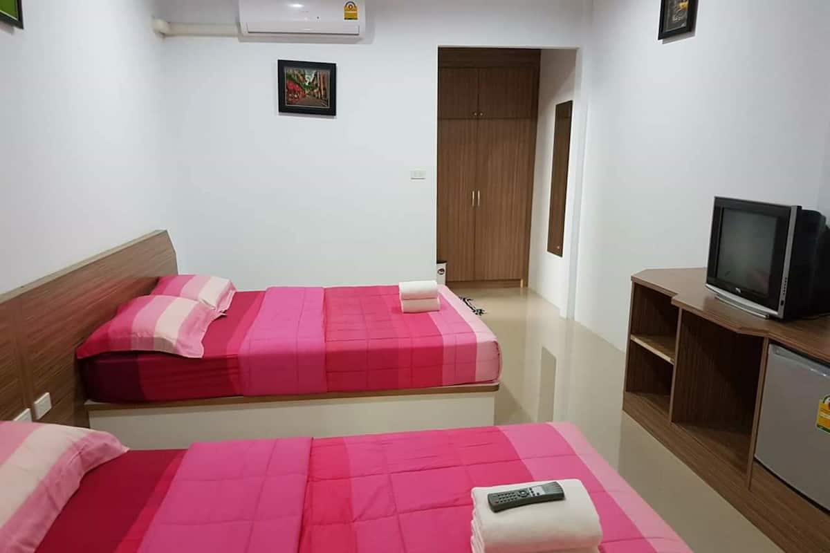 Habitación de hotel con dos camas, un televisor y un armario.