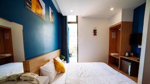 Una habitación de hotel con dos camas, un cabecero de madera, un teléfono junto a la cama, una planta pequeña y un televisor sobre una estantería de madera.