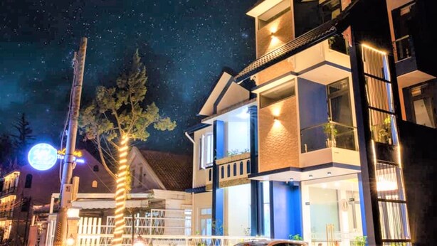 Un edificio moderno de dos pisos con un balcón y un letrero iluminado al fondo.