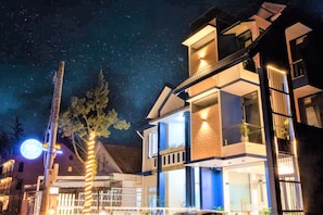 Un bâtiment moderne à deux étages, doté d'un balcon et d'une enseigne lumineuse en arrière-plan.