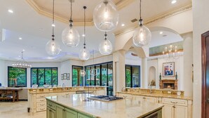 Una cocina amplia con una isla grande, múltiples lámparas colgantes y una chimenea.