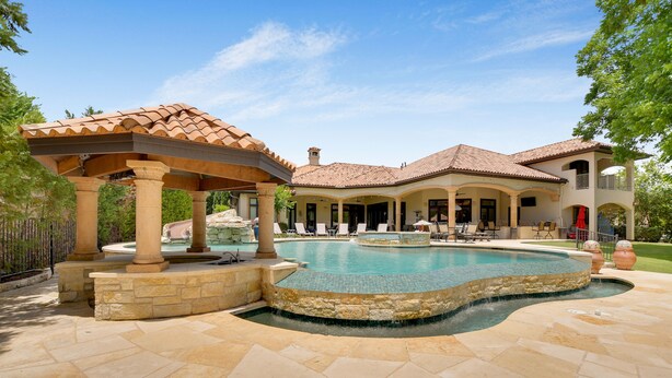 Una piscina con una pérgola y un patio cubierto.