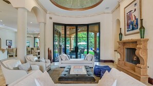 Un salón amplio con chimenea, un ventanal grande y vistas al exterior.