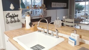Une cuisine avec un évier blanc, un plan de travail en bois et un luminaire suspendu.